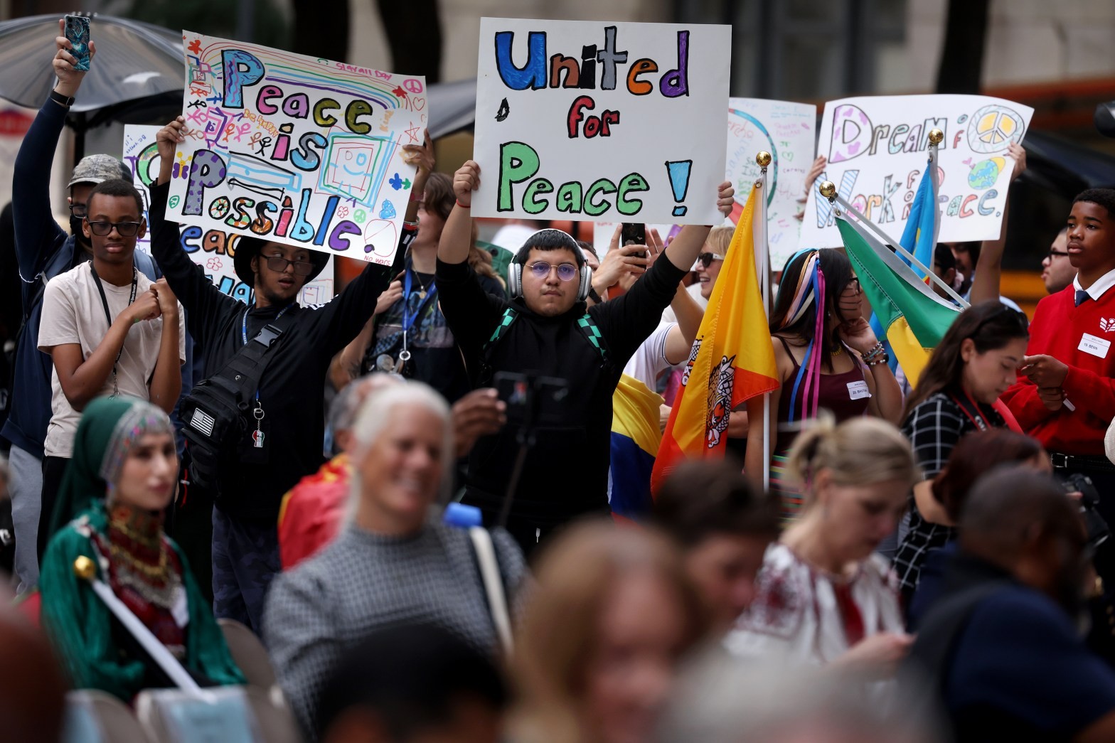 Protesters hold "Peace is Possible" and "United for Peace!" signs at a public gathering. Protesters hold "Peace is Possible" and "United for Peace!" signs at a public gathering.
