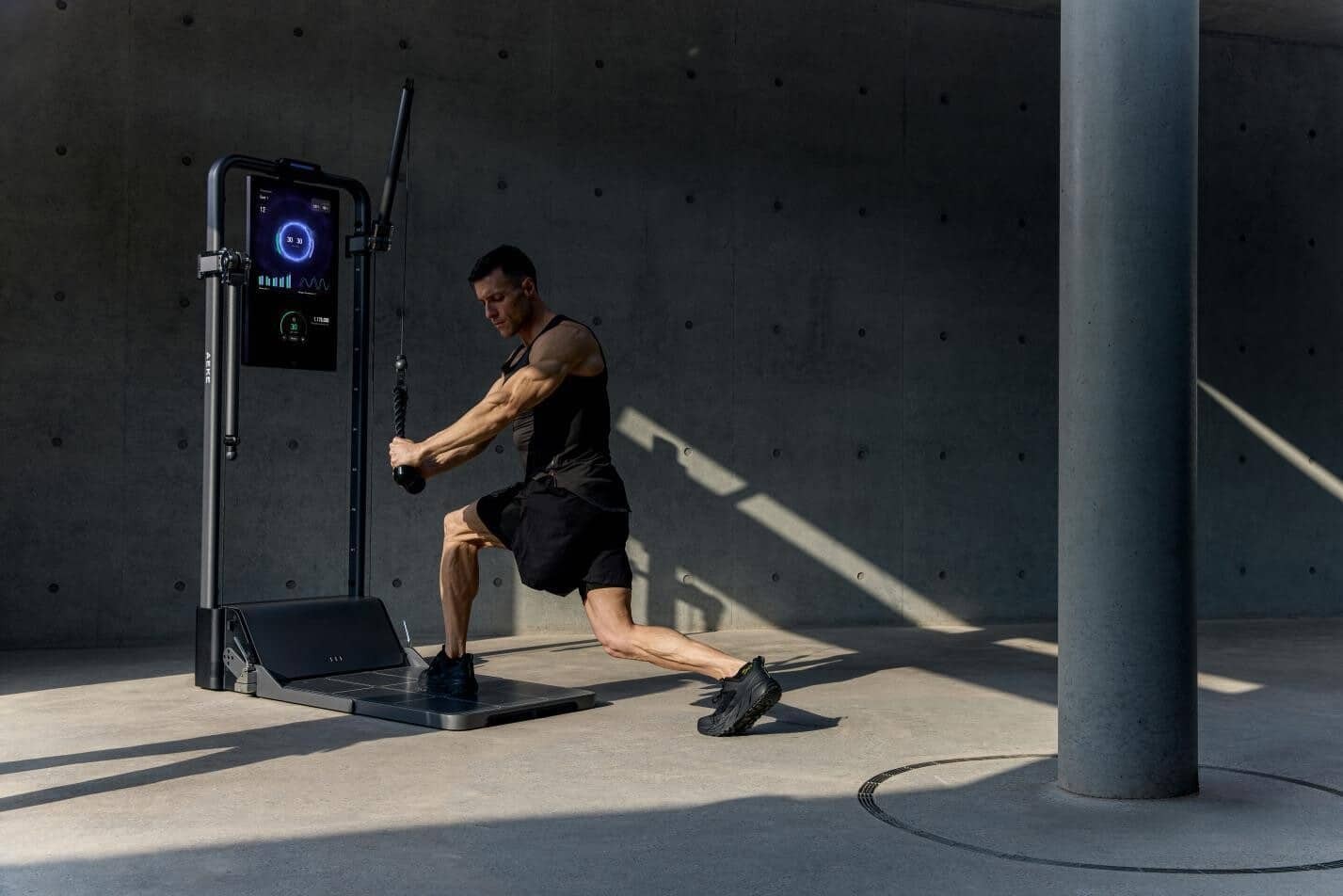 Man pulls rope on cable fitness machine in concrete-walled room. Man pulls rope on cable fitness machine in concrete-walled room.