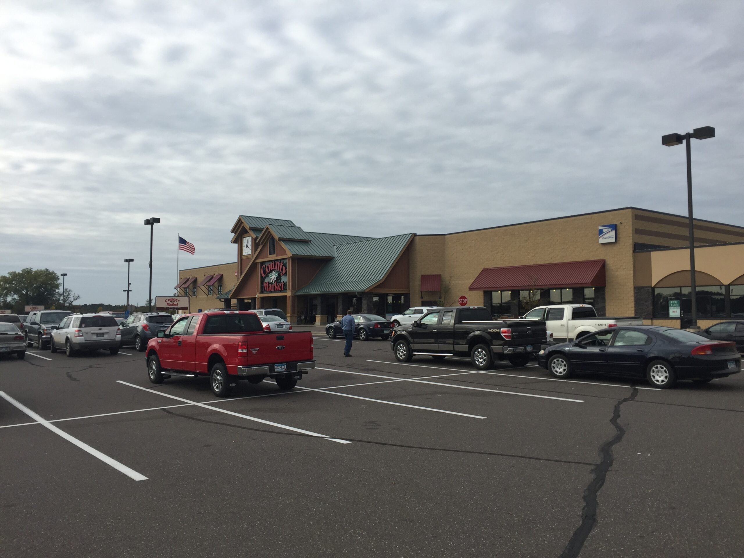 County Market parking lot has multiple vehicles parked under cloudy skies. County Market parking lot has multiple vehicles parked under cloudy skies.