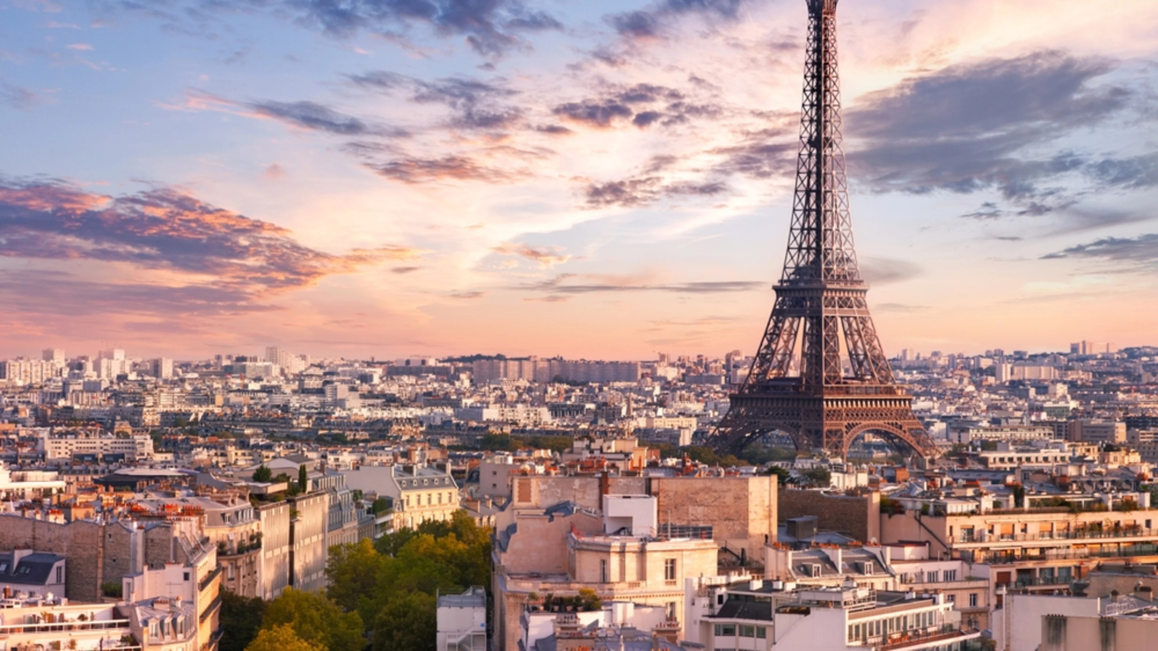 Eiffel Tower stands prominently against a sunset sky over Parisian cityscape. Eiffel Tower stands prominently against a sunset sky over Parisian cityscape.
