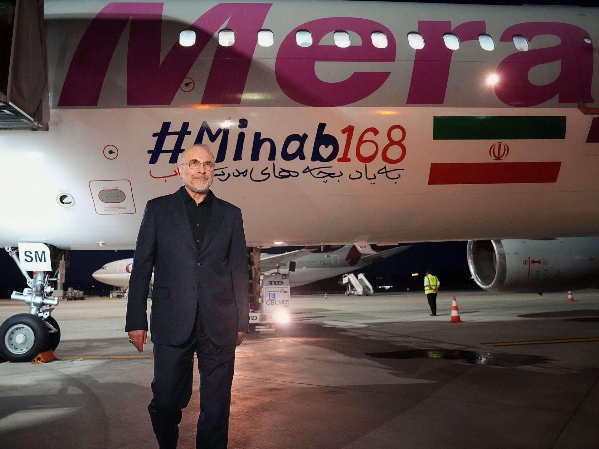 A man in a dark suit stands on an airport tarmac before a Mera-branded aircraft. A man in a dark suit stands on an airport tarmac before a Mera-branded aircraft.
