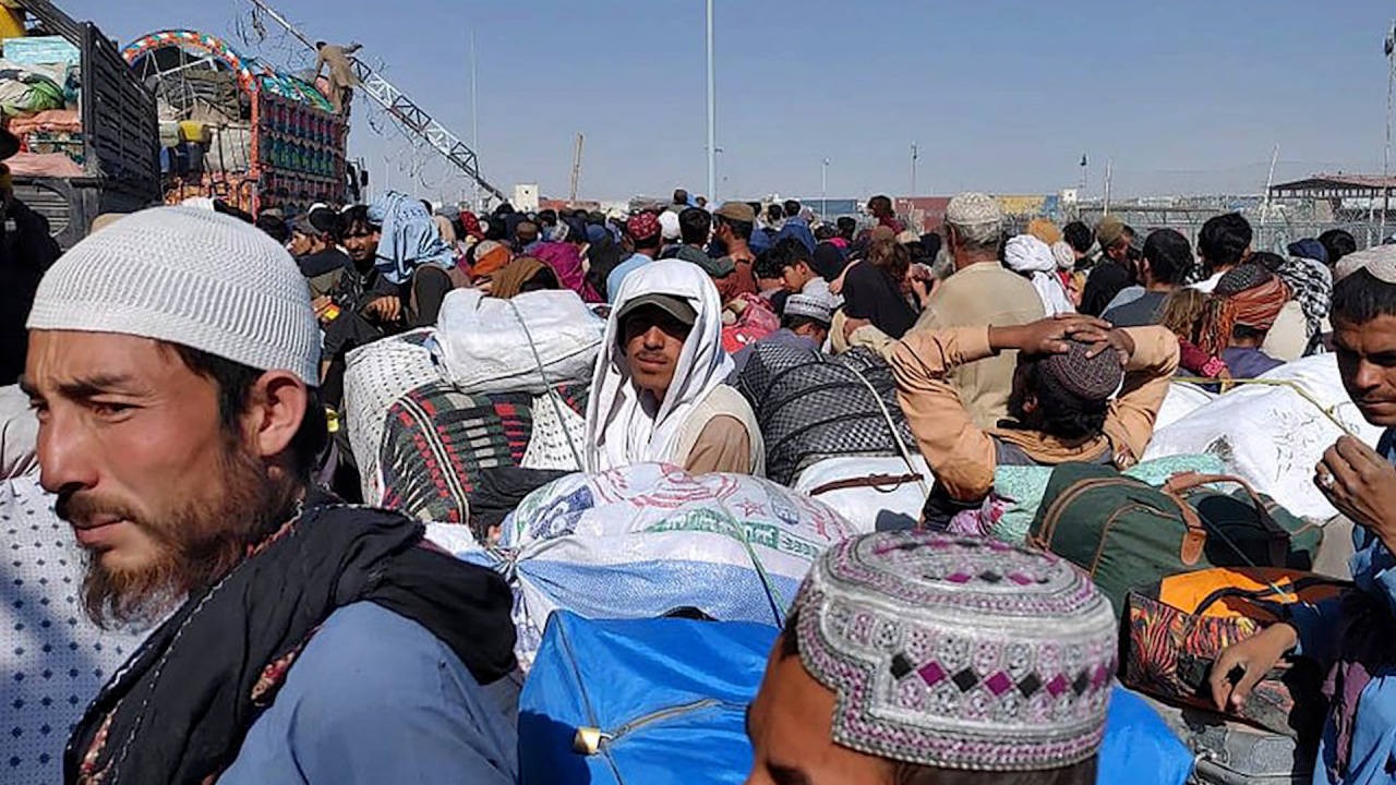 Men carry luggage while gathering near a truck at an outdoor transit area. Men carry luggage while gathering near a truck at an outdoor transit area.