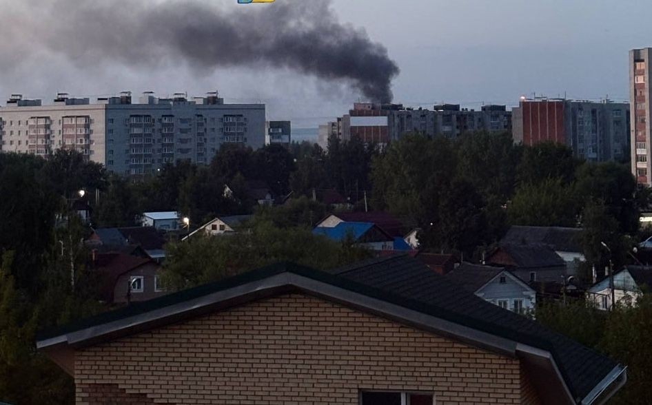 Dark smoke rises above urban residential buildings in a city skyline.