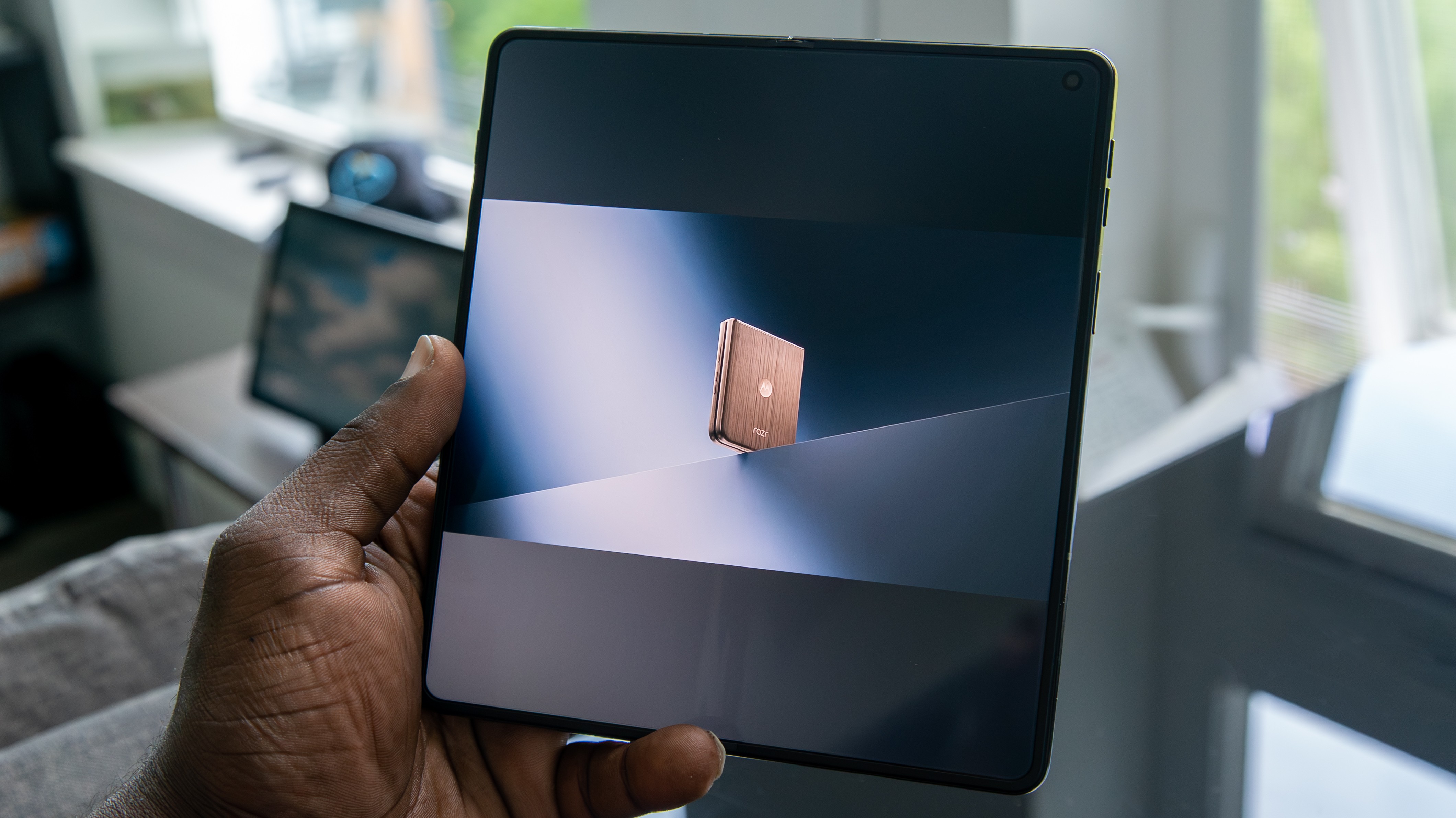Foldable smartphone shows 04:04 on outer screen while one panel stands upright on a wooden table. Foldable smartphone shows 04:04 on outer screen while one panel stands upright on a wooden table.