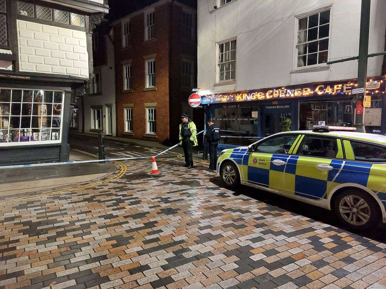 Police officers cordon a street outside King's Corner Cafe at night. Police officers cordon a street outside King's Corner Cafe at night.