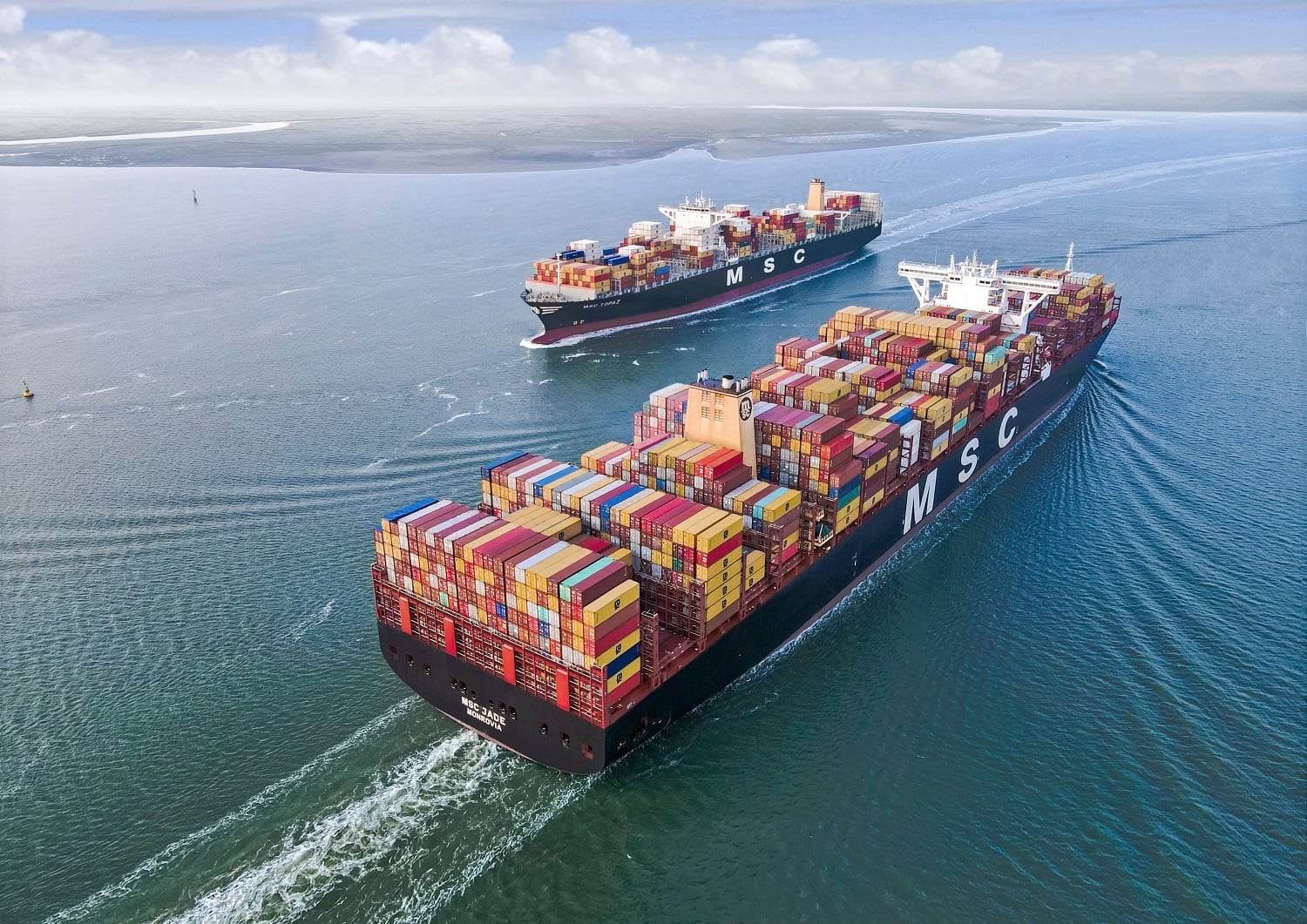 Two MSC container ships sail on calm ocean waters under a clear sky.