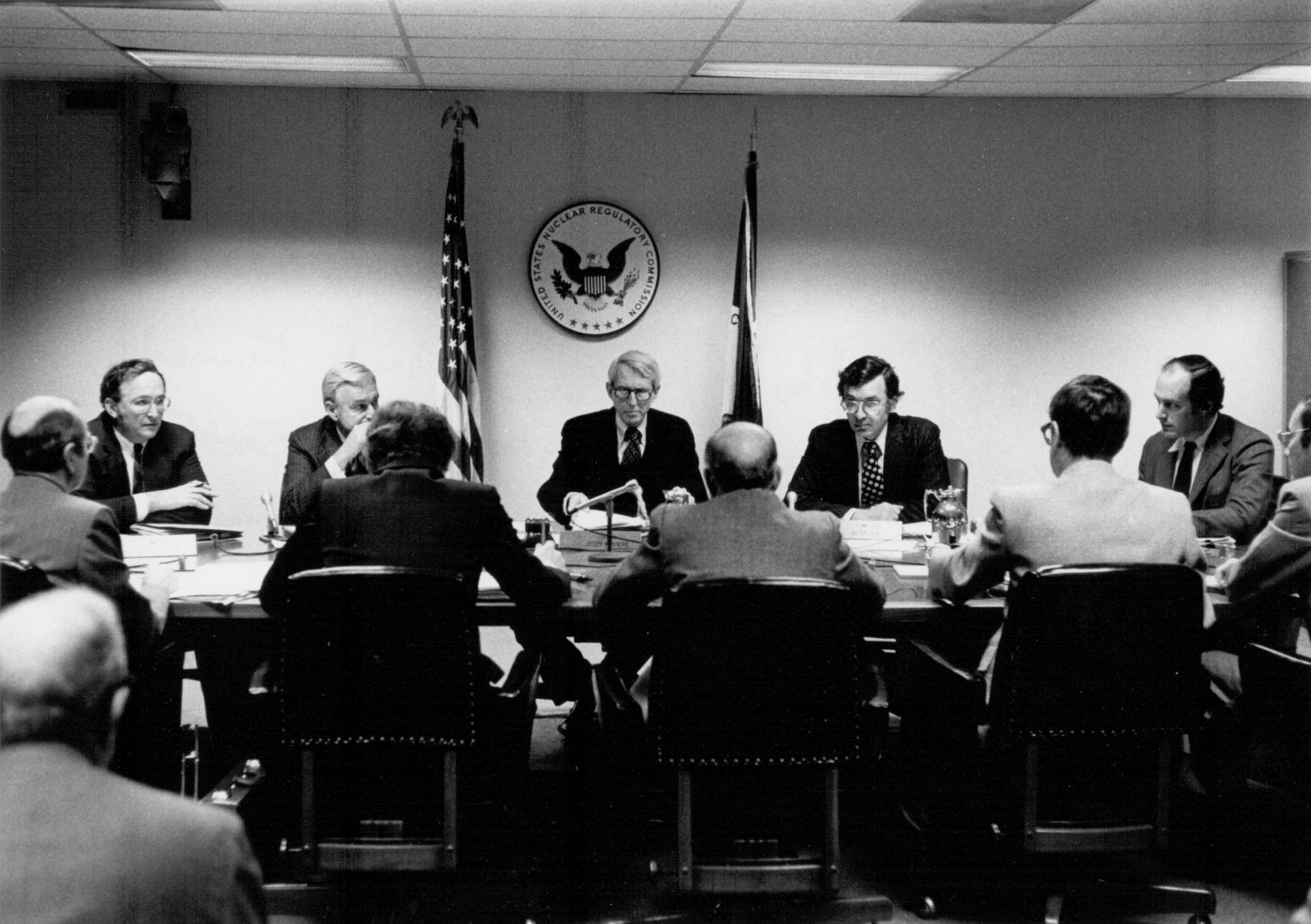 Three men pose at a U.S. Nuclear Regulatory Commission table with a framed award. Three men pose at a U.S. Nuclear Regulatory Commission table with a framed award.