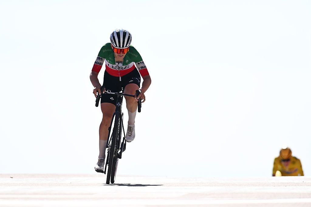 Cyclist in green-red jersey rides bicycle across bright white open terrain. Cyclist in green-red jersey rides bicycle across bright white open terrain.