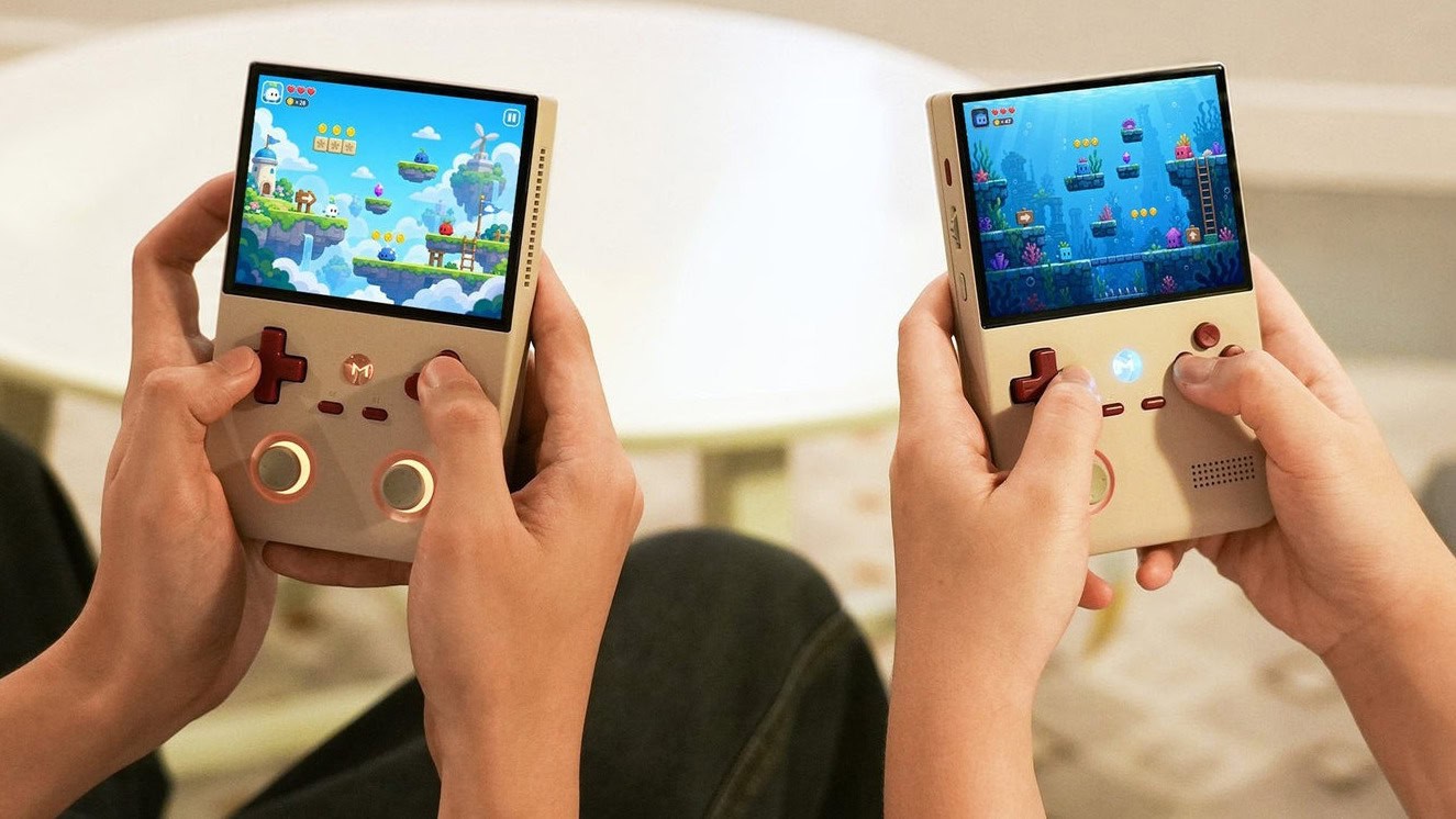 Two people hold handheld gaming consoles, each playing distinct games indoors. Two people hold handheld gaming consoles, each playing distinct games indoors.