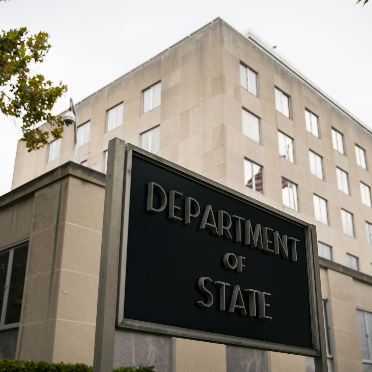 A black "DEPARTMENT OF STATE" sign stands before a beige government building. A black "DEPARTMENT OF STATE" sign stands before a beige government building.