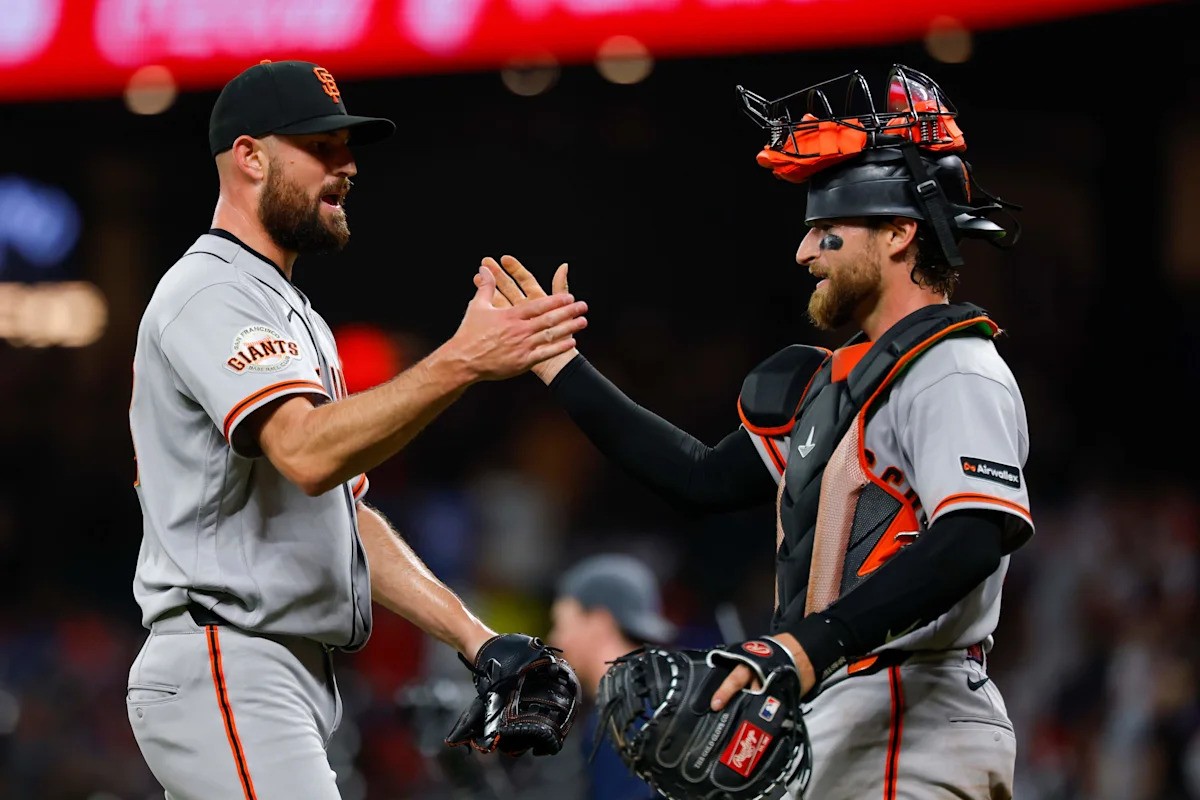 Two San Francisco Giants players high-five during a baseball game. Two San Francisco Giants players high-five during a baseball game.