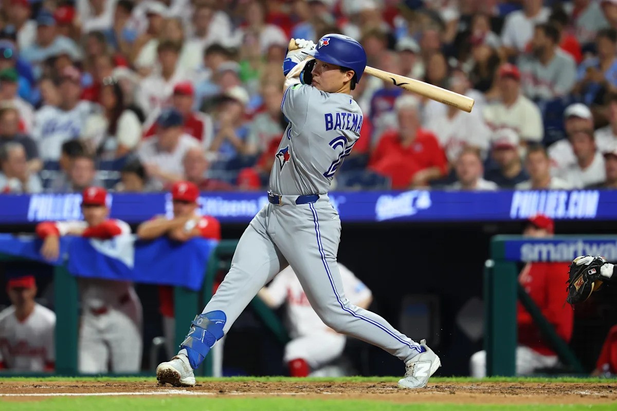 Toronto Blue Jays batter Bate-man swings bat at home plate in a crowded stadium.