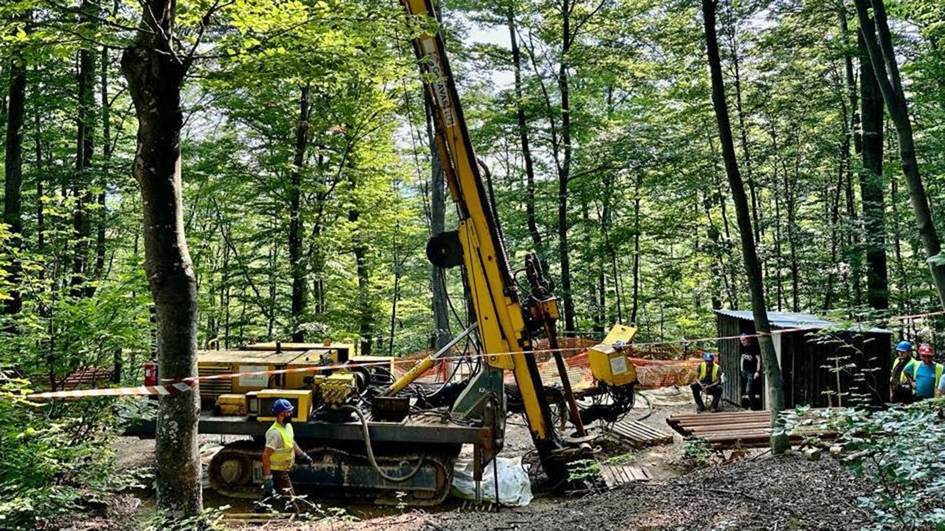 Workers operate yellow crane machinery at a forest construction site. Workers operate yellow crane machinery at a forest construction site.