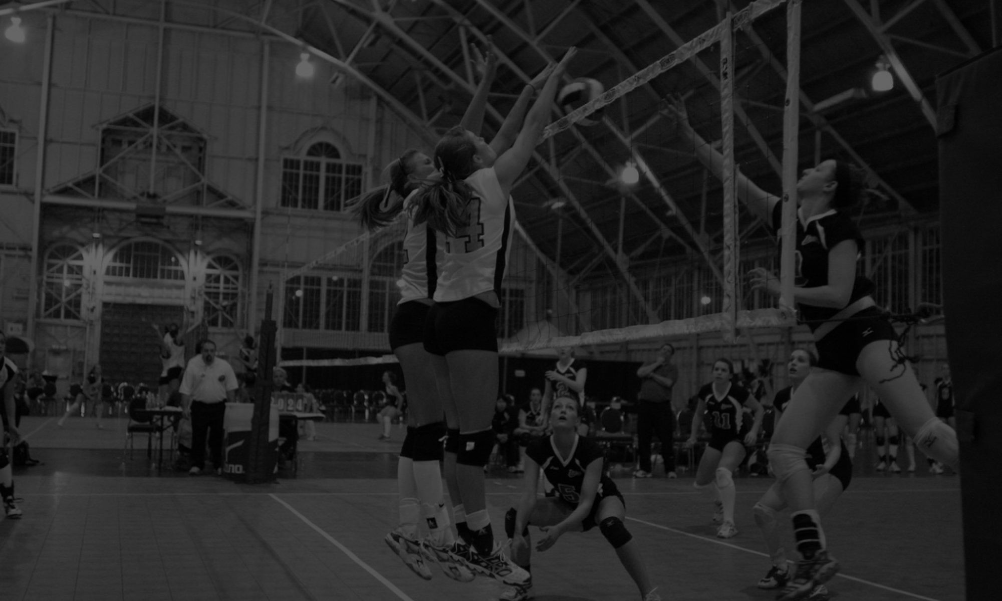 Volleyball players spike and block during an indoor gymnasium match. Volleyball players spike and block during an indoor gymnasium match.