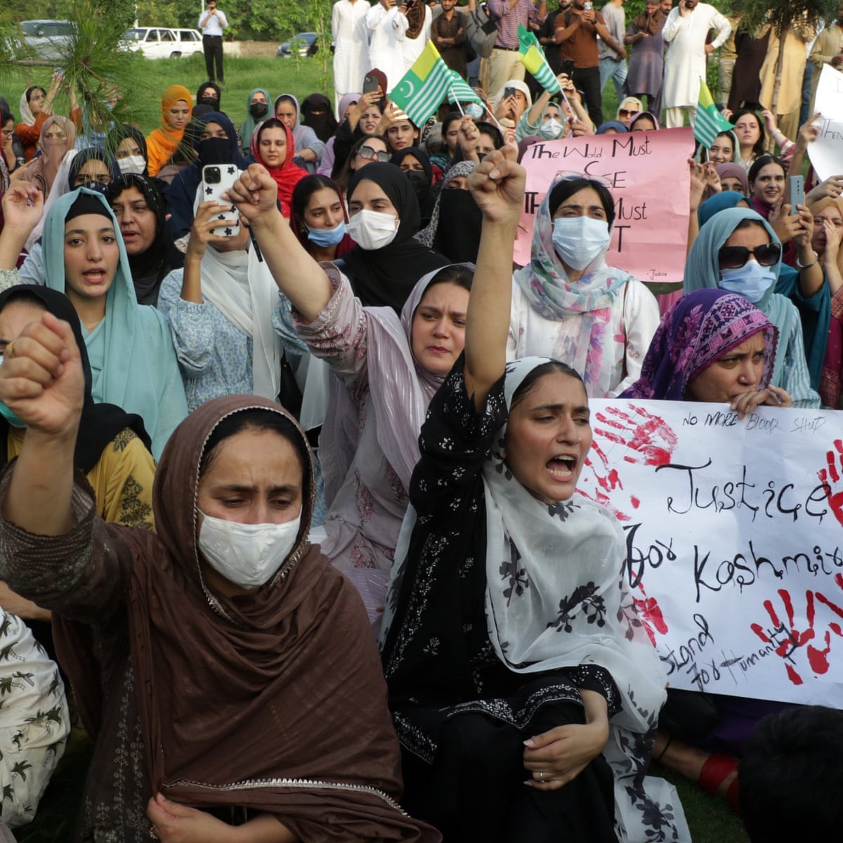 Women protest outdoors holding signs and raising fists. Women protest outdoors holding signs and raising fists.