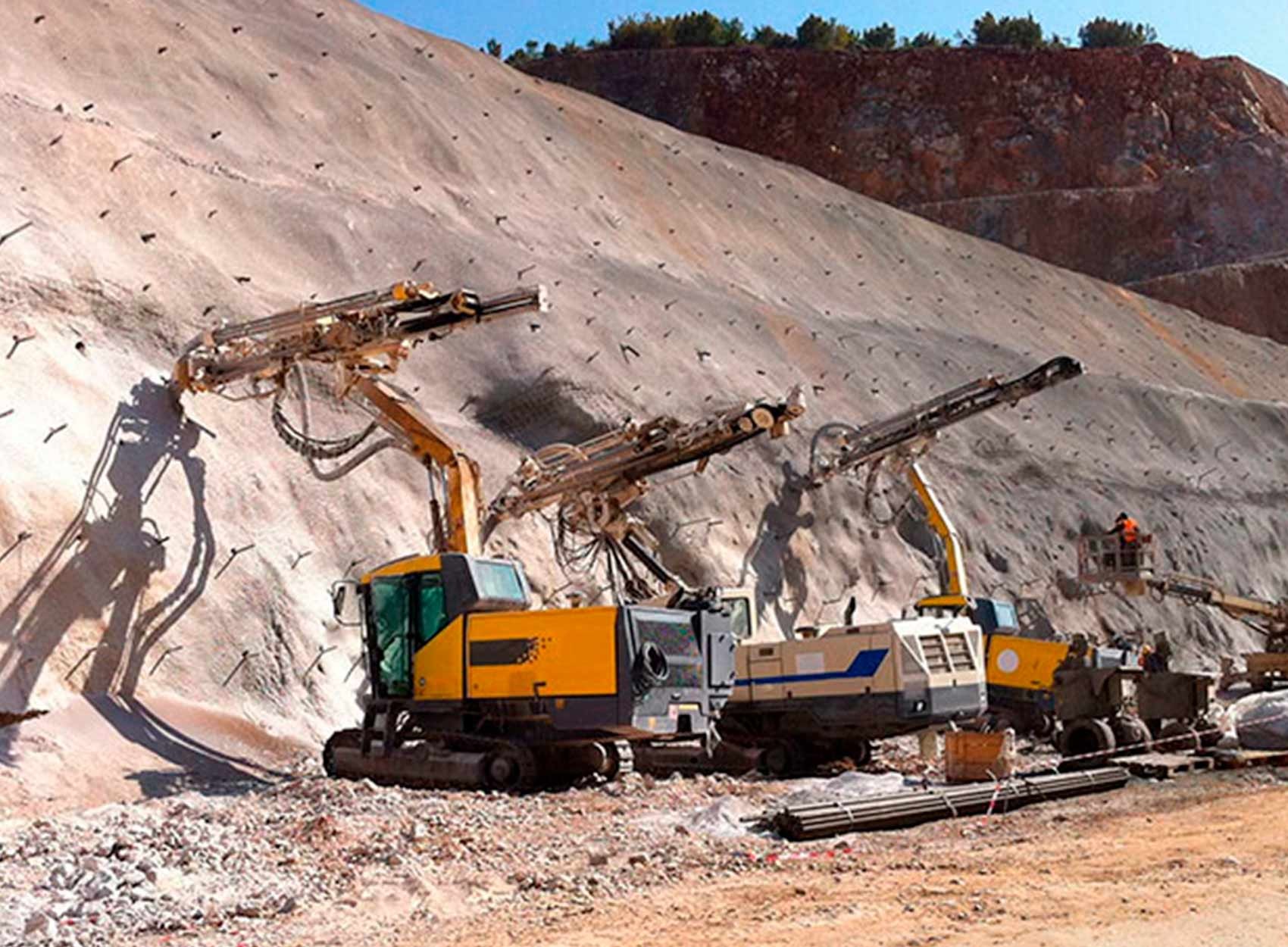 Three yellow mining drills operate on a steep quarry slope in an open-pit mine site. Three yellow mining drills operate on a steep quarry slope in an open-pit mine site.