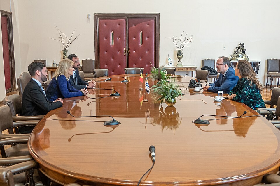 Group meets at a large wooden conference table in an official room with microphones. Group meets at a large wooden conference table in an official room with microphones.