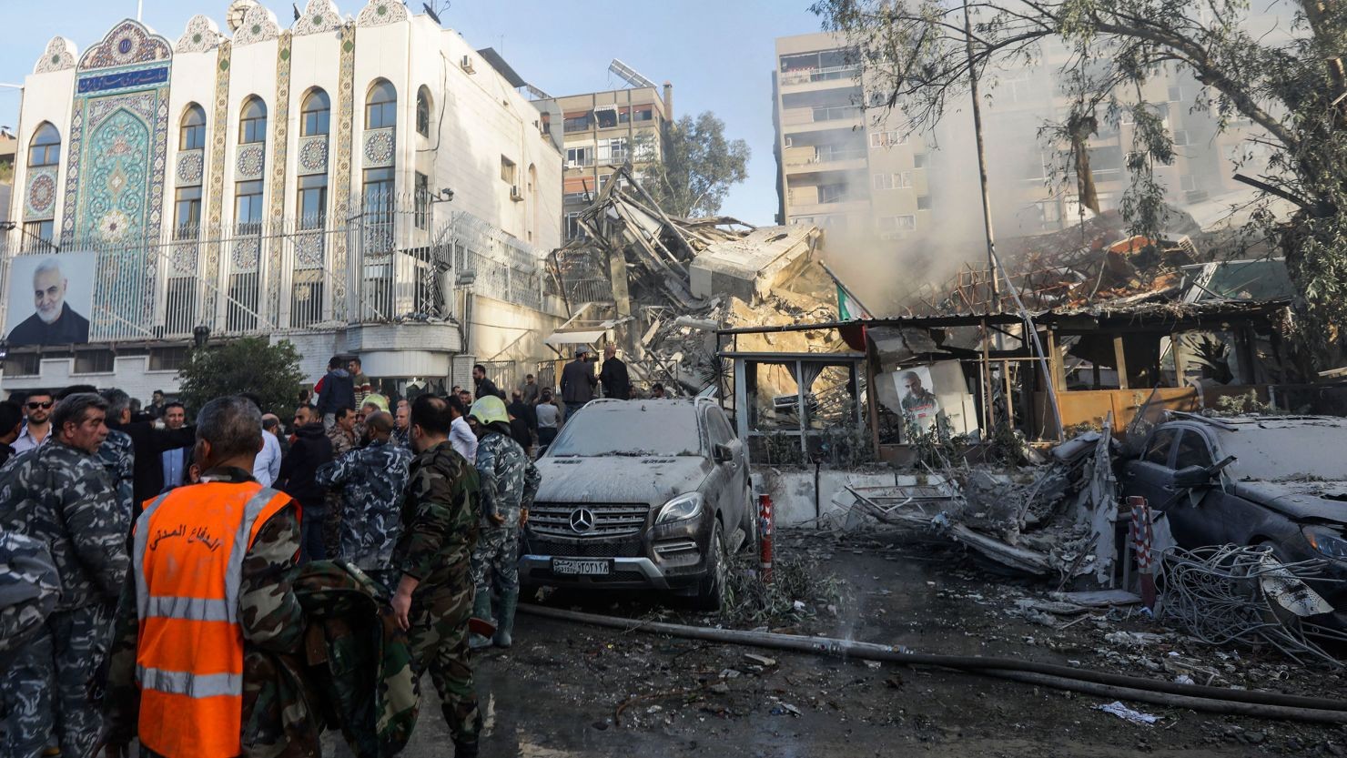 Emergency personnel survey destroyed buildings and vehicles after an explosion in a city. Emergency personnel survey destroyed buildings and vehicles after an explosion in a city.