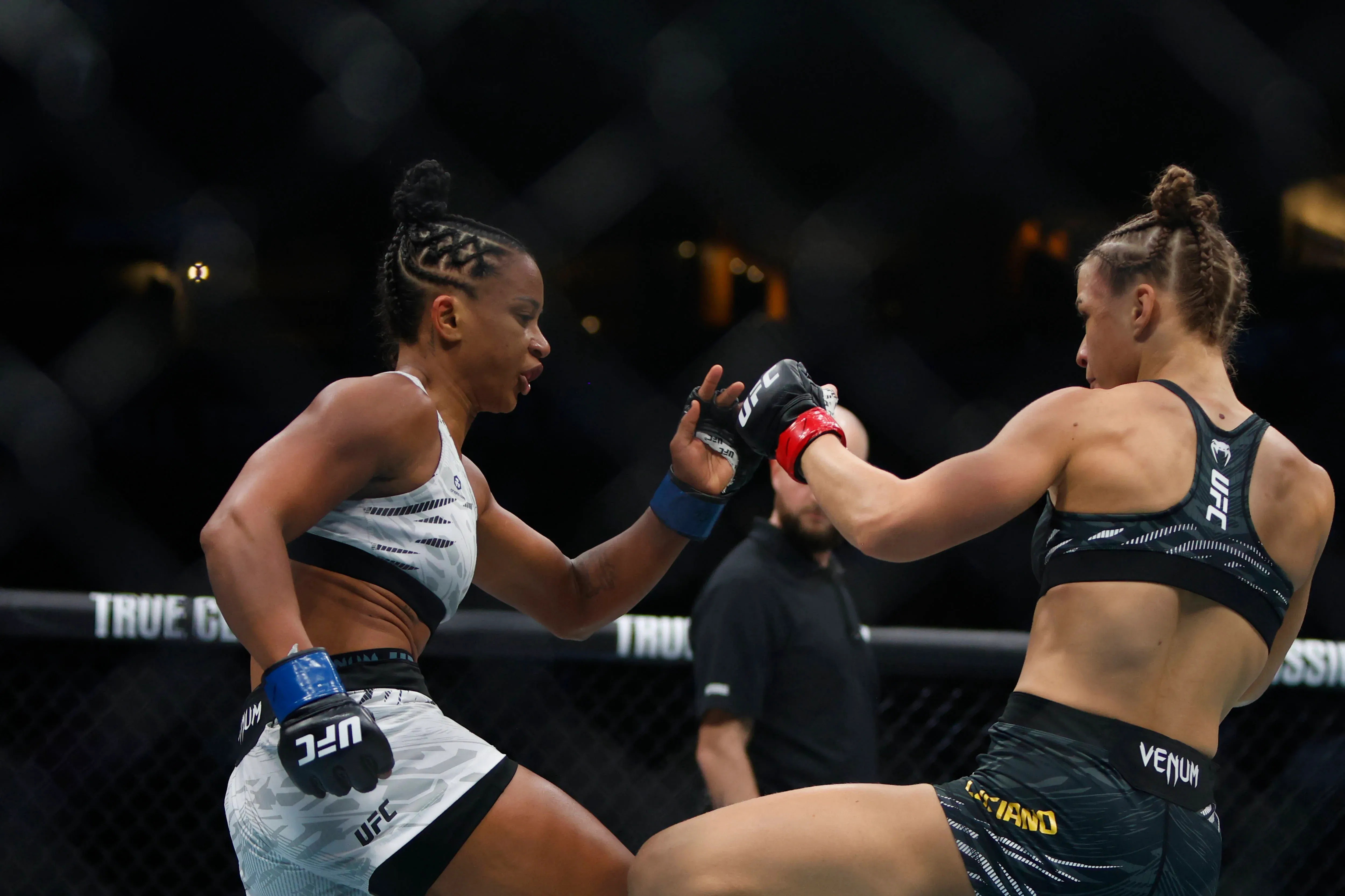 Two female MMA fighters engage in combat inside a UFC octagon cage.