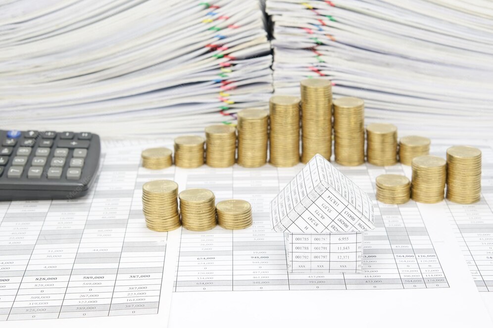 Coins stacked on financial spreadsheets with a calculator and paper piles. Coins stacked on financial spreadsheets with a calculator and paper piles.